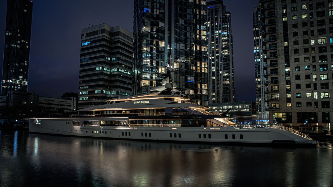 Luxury yacht anchored at Canary Wharf in Londons skyline at night.